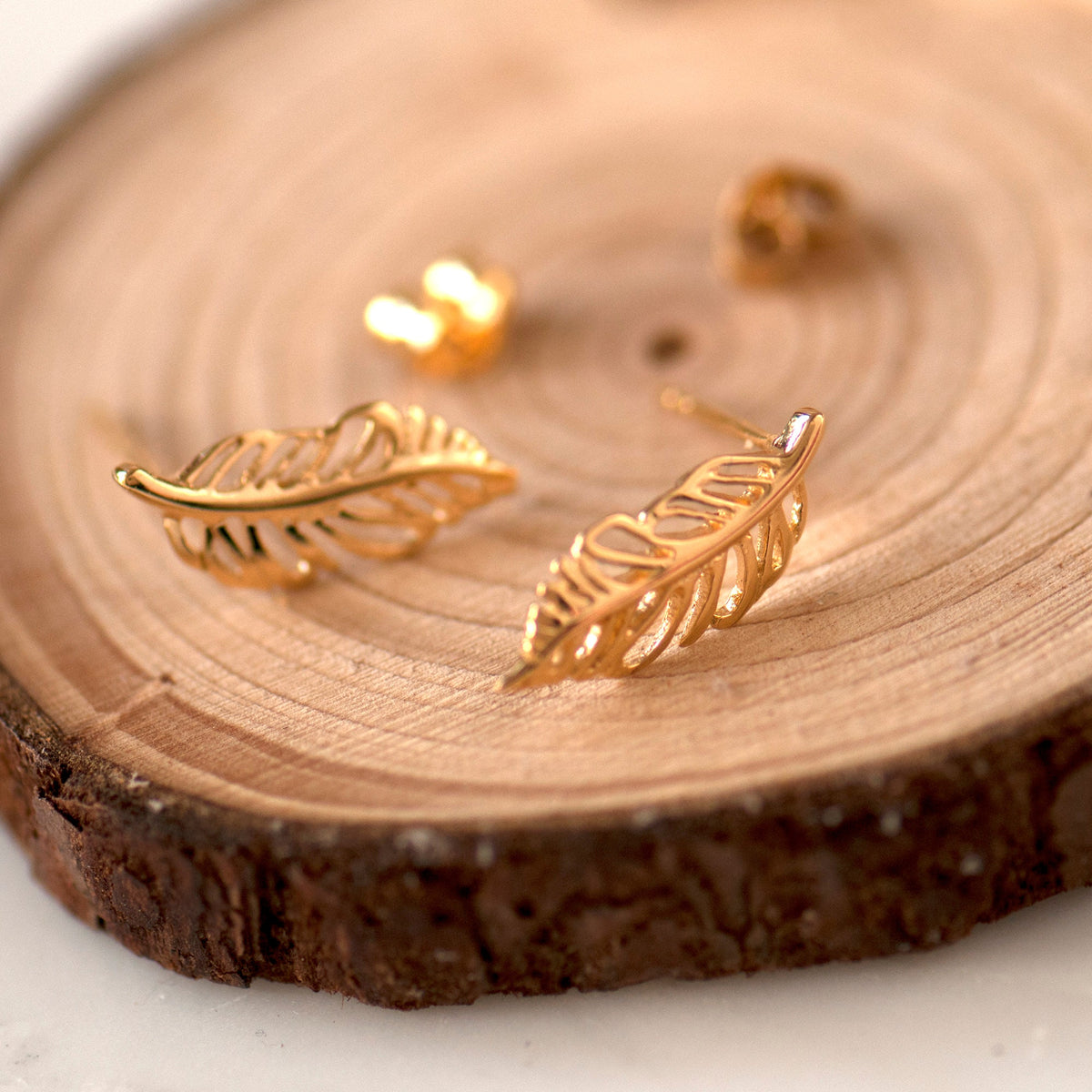 gold outline stud earrings feather design