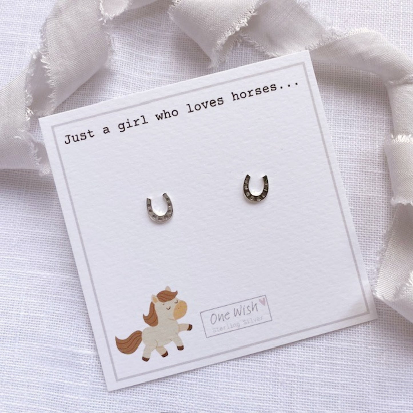 Horseshoe earrings on a card with text and a cute horse illustration.