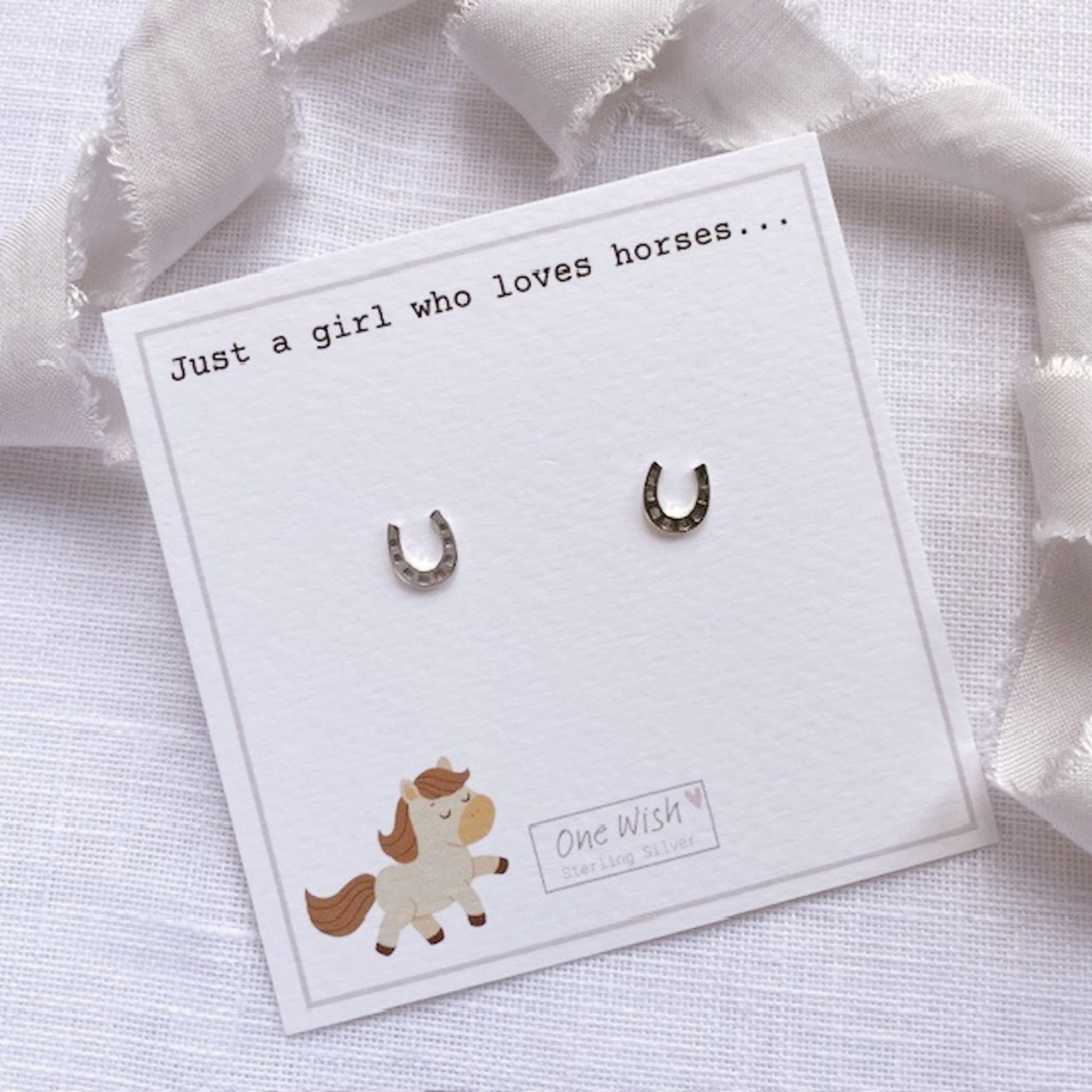 Horseshoe earrings on a card with text and a cute horse illustration.