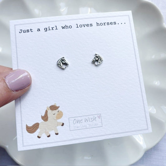 Silver horse earrings on a card with 'One Wish' branding, held by a hand.