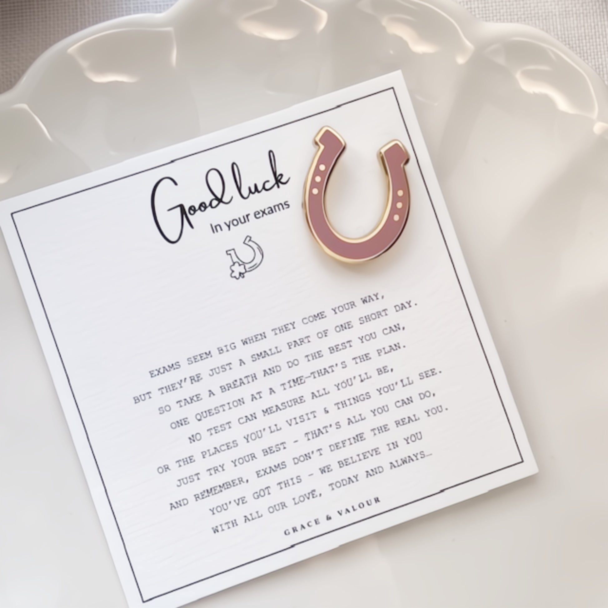 Good luck card with a pink horseshoe charm on a white dish