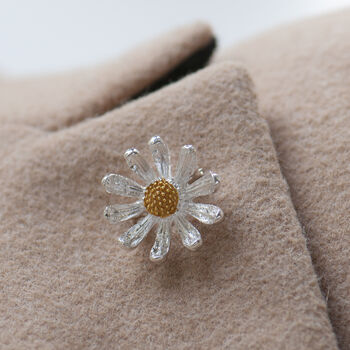 Tiny silver and gold daisy brooch on a lapel