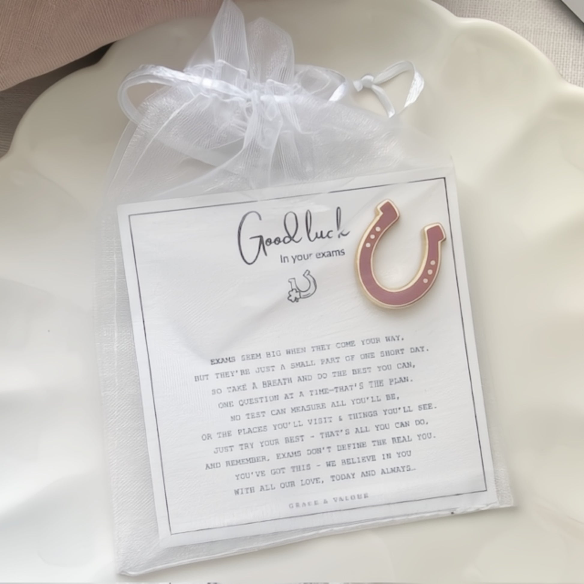 Pink horseshoe enamel pin on a card with a bespoke good luck in your exams gift card.