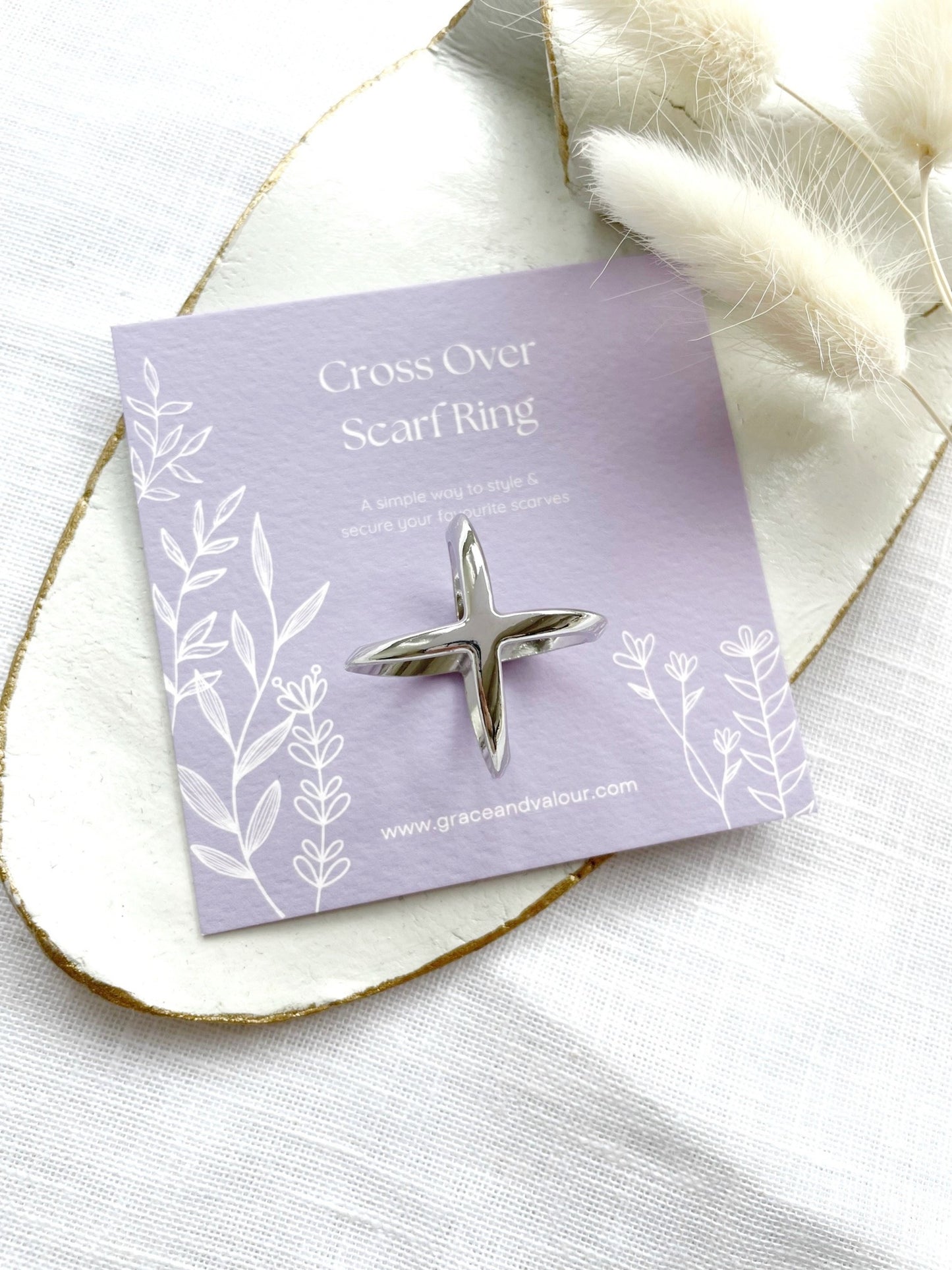 Silver cross-shaped scarf ring on a purple gift card