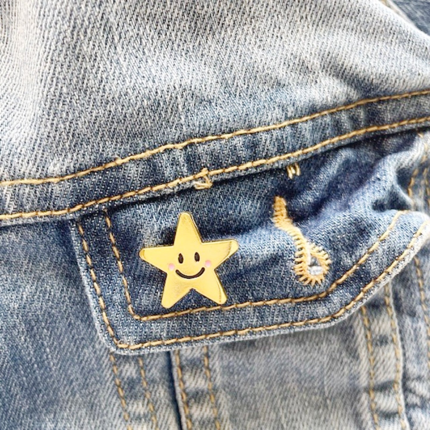 Gold star-shaped pin on a denim jacket