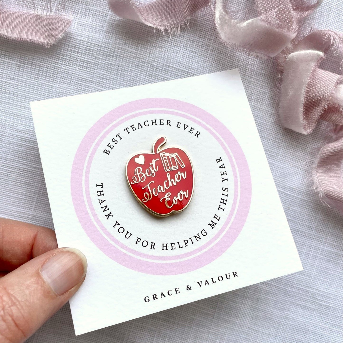 Red apple-shaped enamel pin on a card with 'Best Teacher Ever' text.