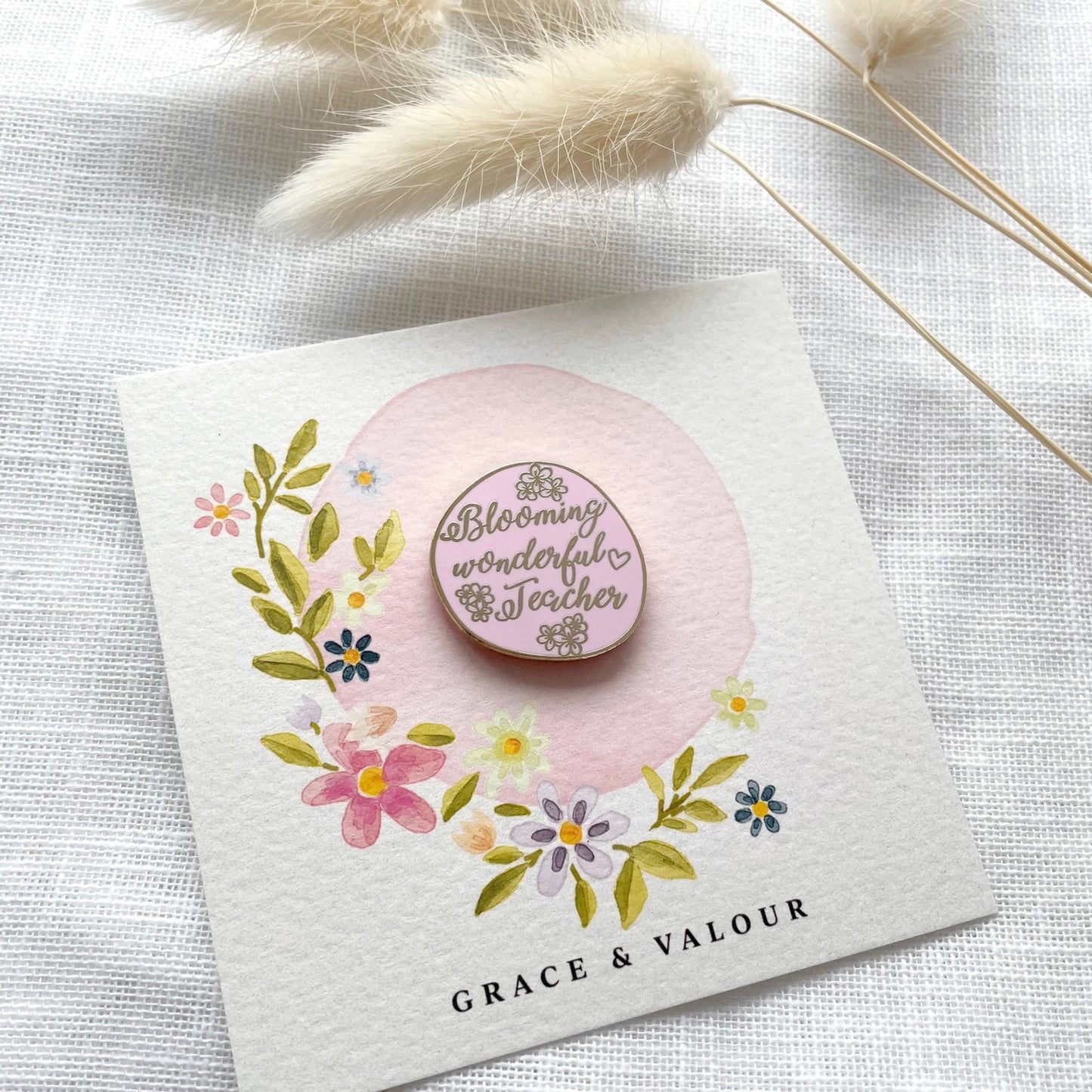 Pink teacher pin with floral design on a card, featuring the text 'Blooming wonderful teacher' 