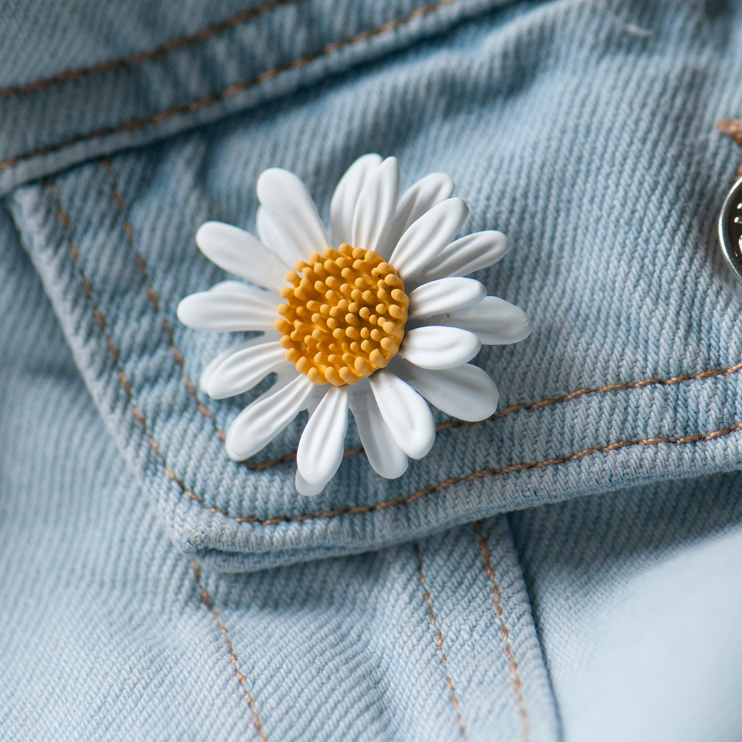Daisy-shaped brooch on a denim jacket