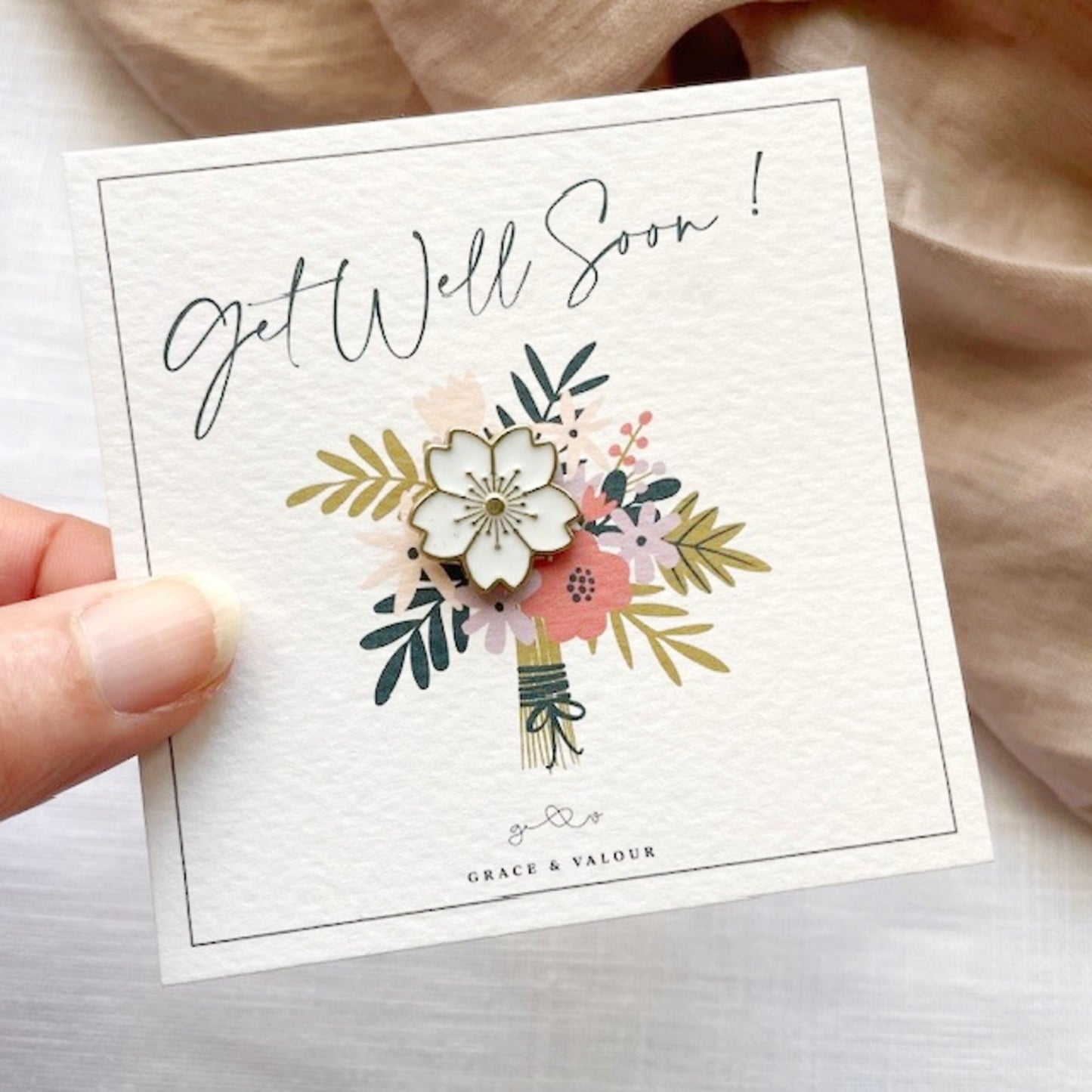 Get Well Soon bunch of flowers gift card with a white enamel blossom pin nestled among the flowers