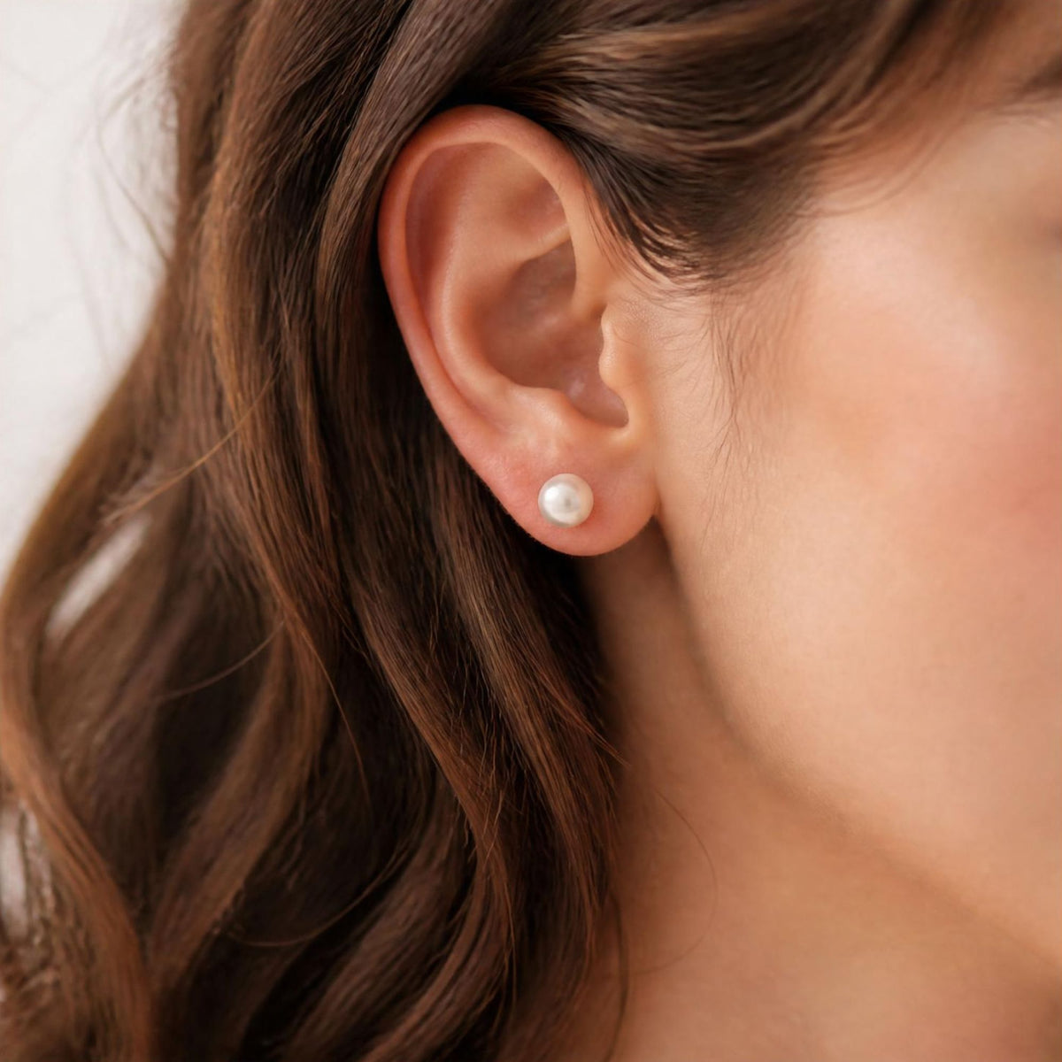 model with dark hair wears 6mm white freshwater pearl stud earrings