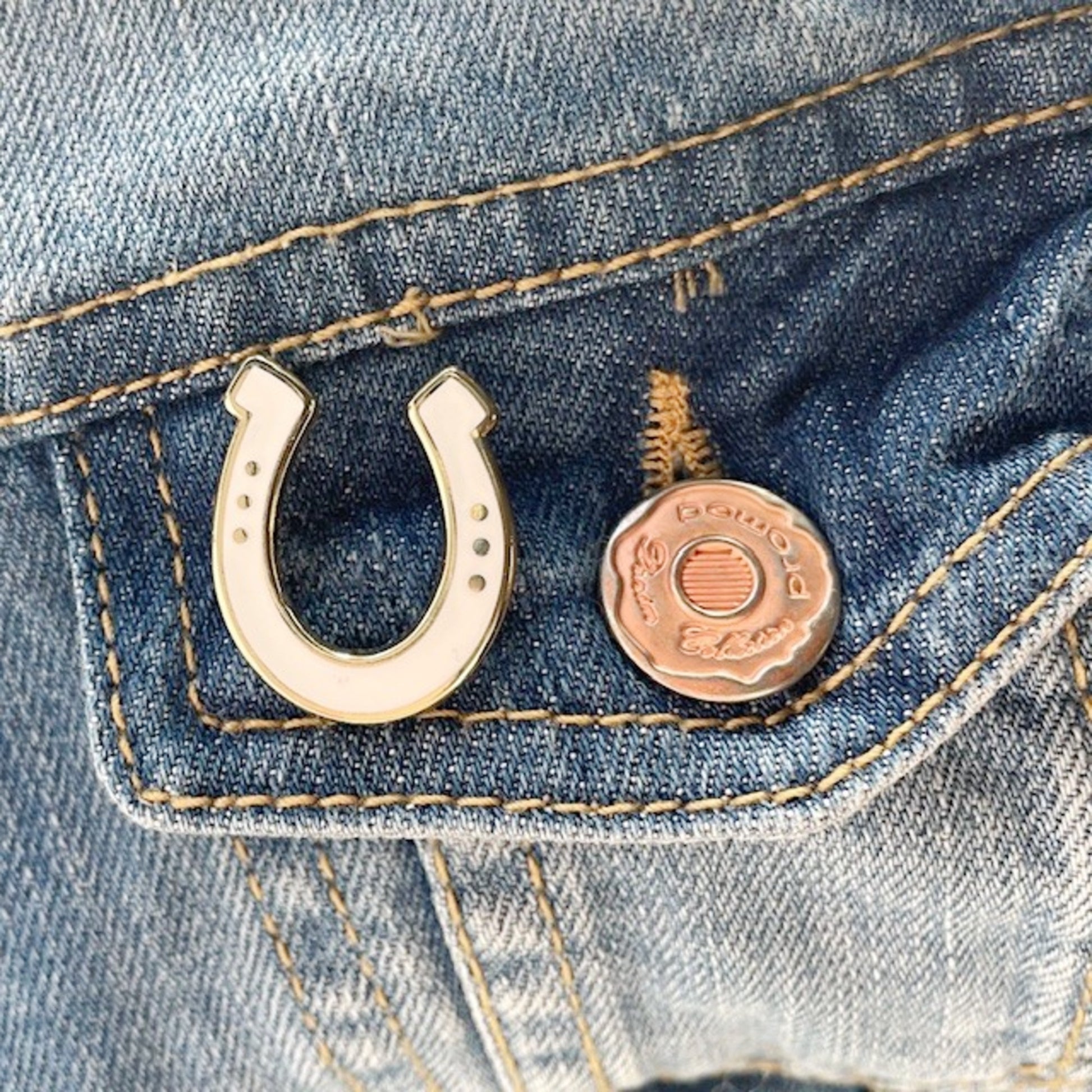 White and Gold Horseshoe-shaped pin on a denim background